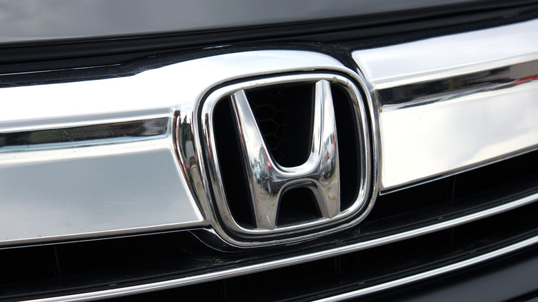 A close-up shot of a Honda logo on the grill of a black car, with the logo and grill being in silver