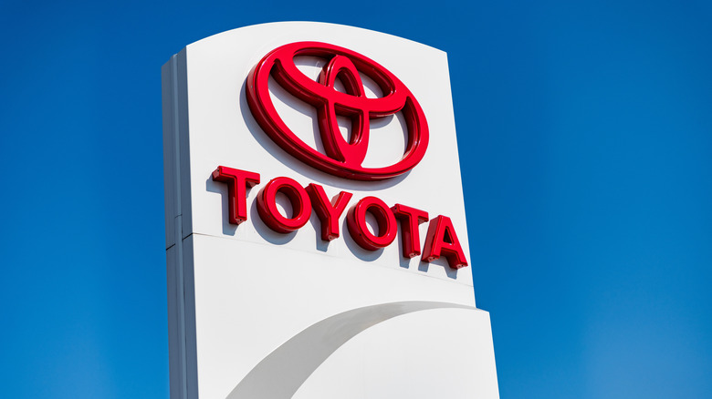 A Toyota logo on a pillar displayed against a clear blue sky