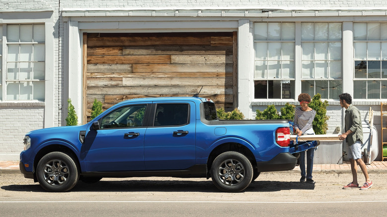 Side view of blue Ford Maverick pickup being loaded with plywood.