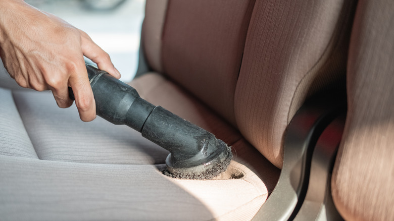 person vaccuming backseat of car