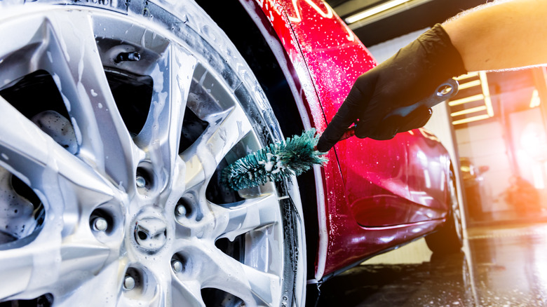 person cleaning wheel with brush