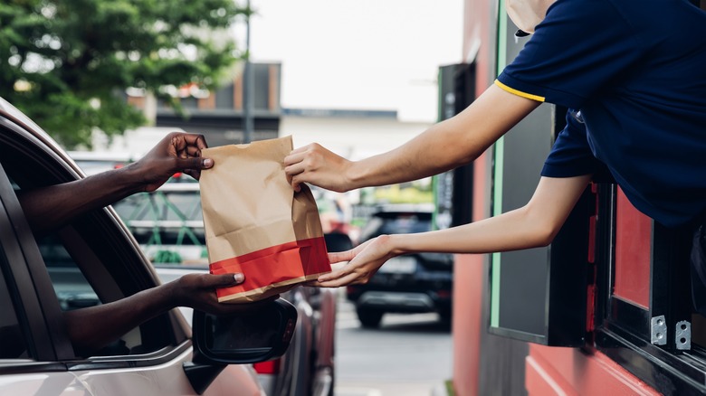 A passenger picking up food from a drive-thru window