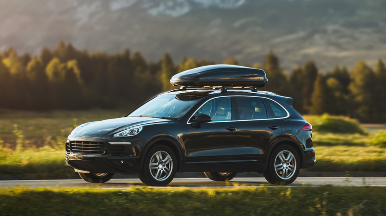Stock photo of an suv parked on a road with a roof box attached to it
