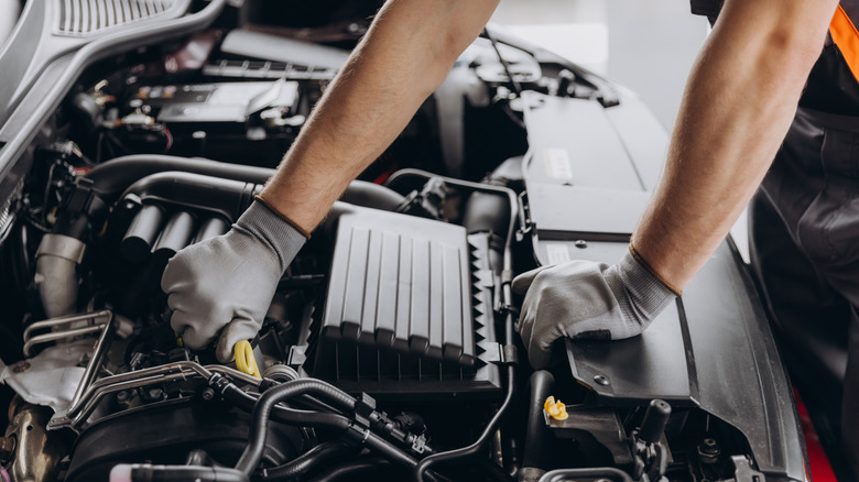 Auto mechanic wearing gloves inspecting an engine