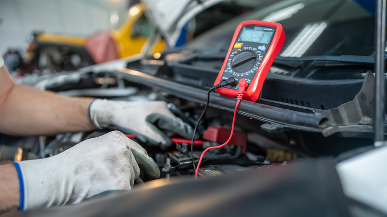 Mechanic checking voltage car battery