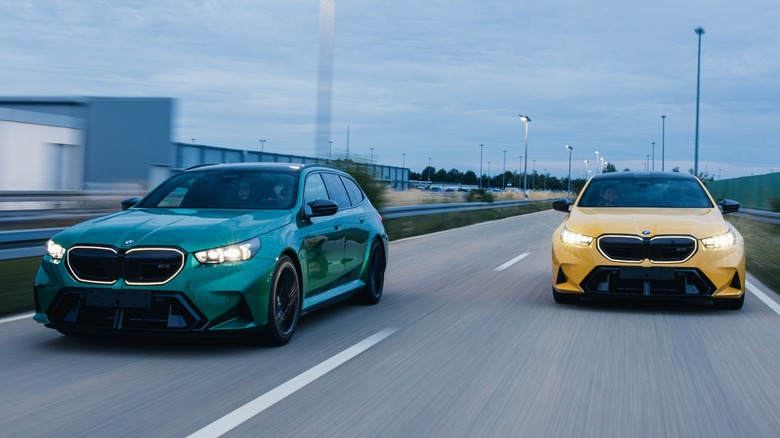 Green and yellow BMW M5 Tourings driving at speed on a straight road