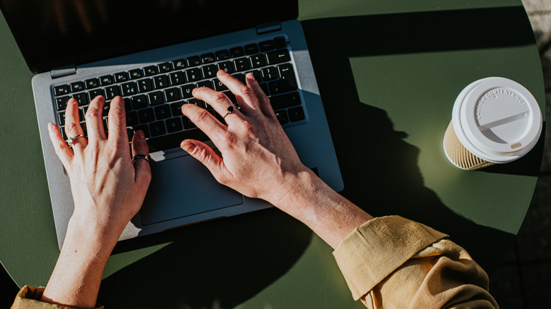 Corporate image of hands typing on a laptop keyboard in an outdoor environment, perhaps a balcony, a garden or a rooftop terrace.