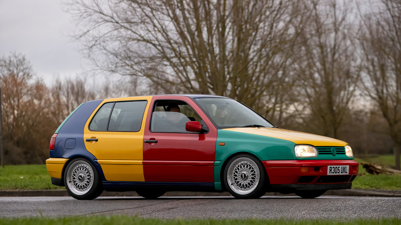 A 1990s multi-color VW Golf Harlequin parked on the road.
