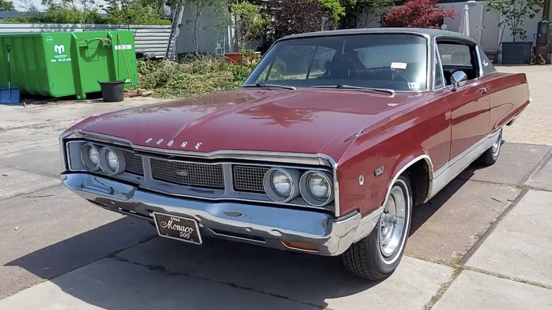 A 1969 Dodge Monaco 500 hardtop coupe finished here in a dark metallic red paint standing in a sunny driveway.