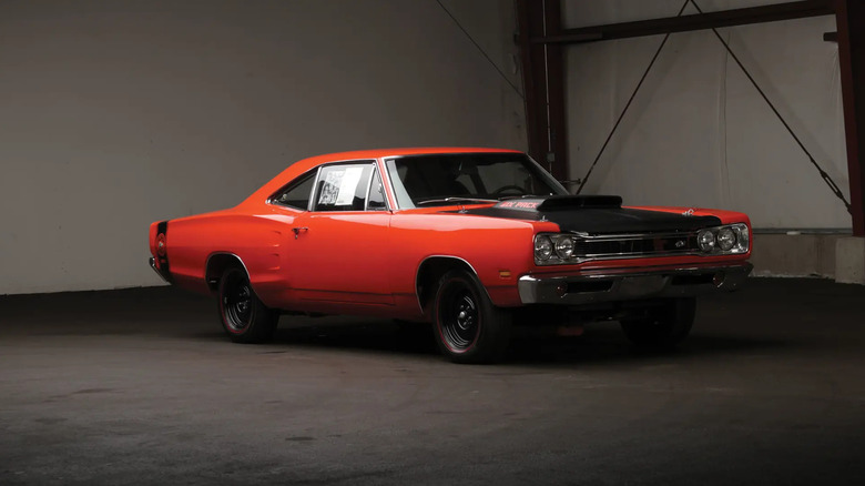 An orange and black 1969.5 Dodge Super Bee optioned with the A12 performance package inside a dark room.