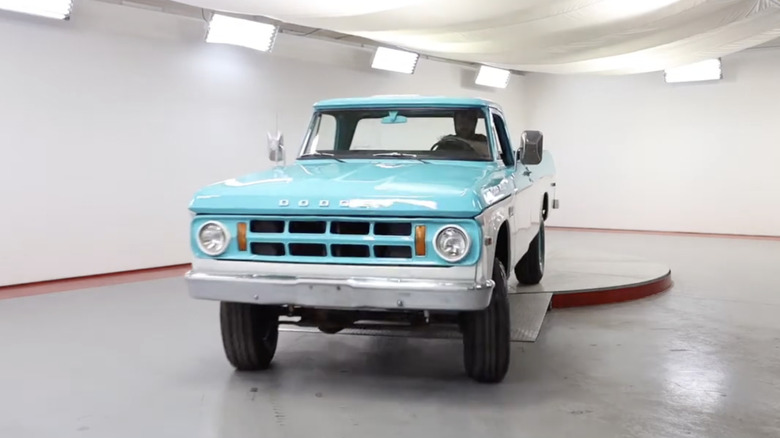 A light blue and white 1969 Dodge W200 Power Wagon 3/4 ton pickup truck parked inside a warehouse.