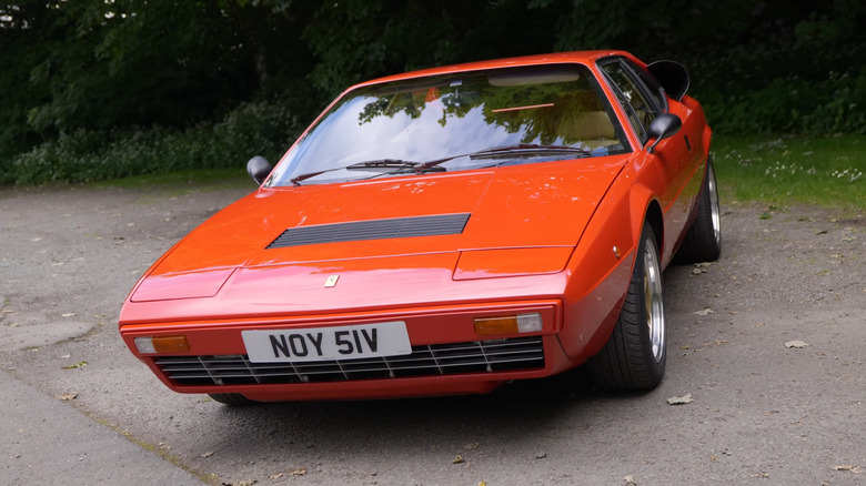 A 1980 Ferrari Dino 308 GT4 finished in the classic red Ferrari paint, parked at an angle at the side of a road.