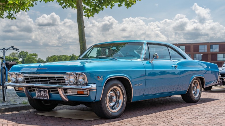 a blue 1965 Chevrolet Impala SS on a brick driveway