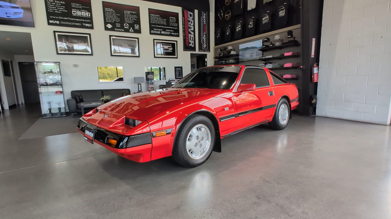 A red 1985 Nissan 300ZX inside a car dealership, front-left 3/4 view