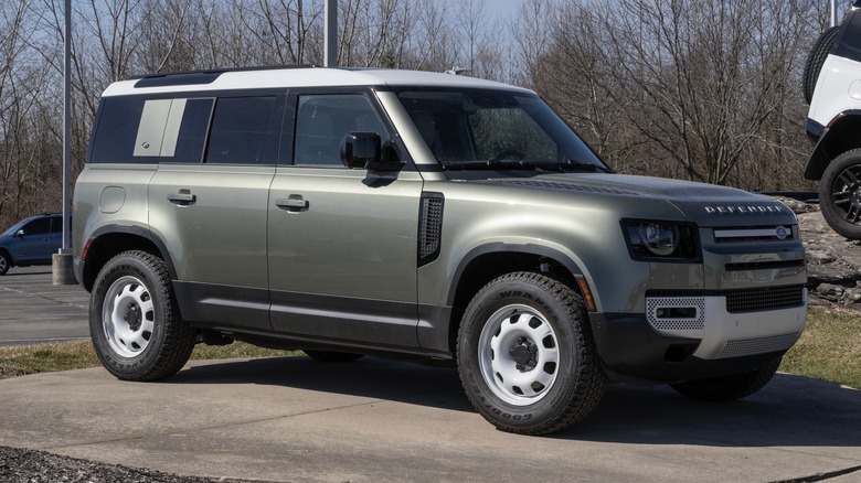 Green Land Rover Defender 110 parked on cement slab
