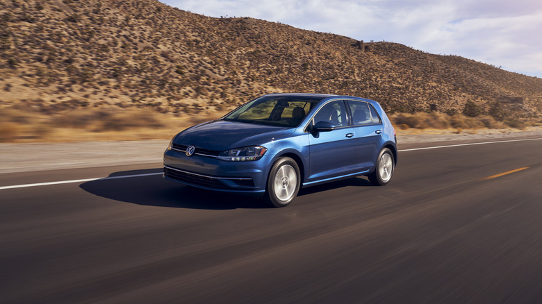 Blue 2021 Volkswagen Golf hatchback seen from front left driving on a desert road