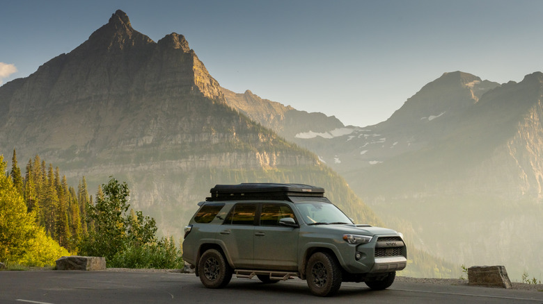 A teal 4Runner on a road trip parked with mountains in its rear view