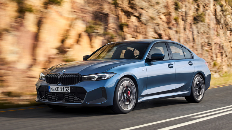 Front 3/4 view of blue BMW 3-Series driving on canyon road.