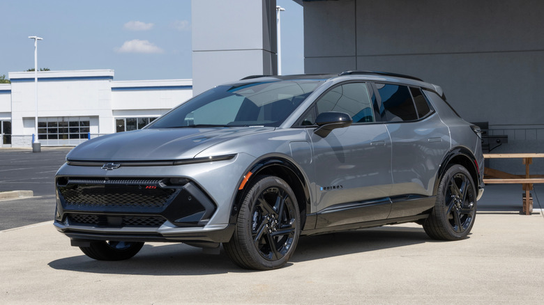 Front 3/4 view of gray Chevy Equinox EV RS parked in front dealership.