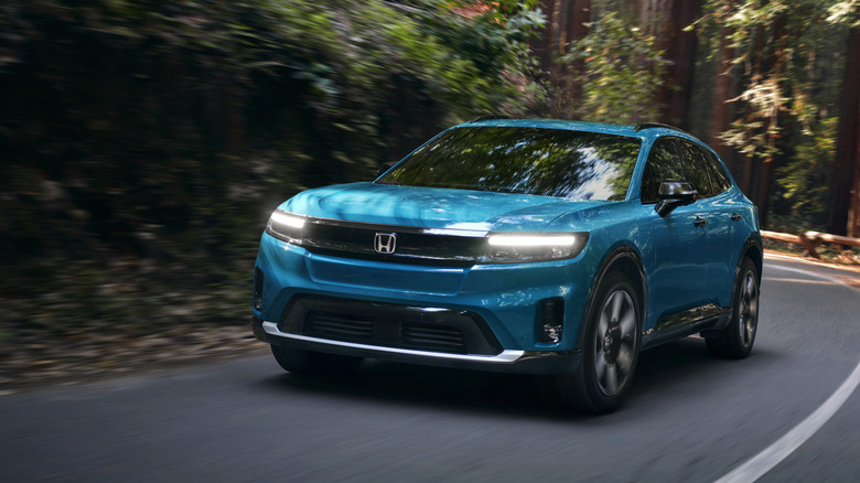 Front view of blue Honda Prologue SUV driving on forest road.