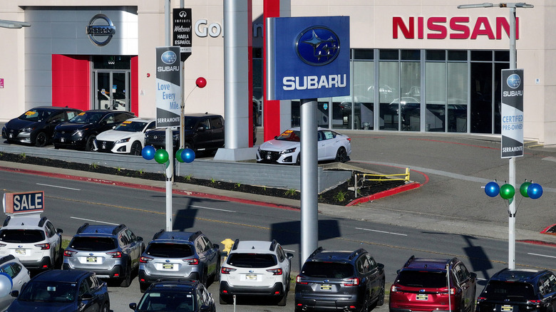 Overhead view of Subaru and Nissan dealership lots filled with new cars.