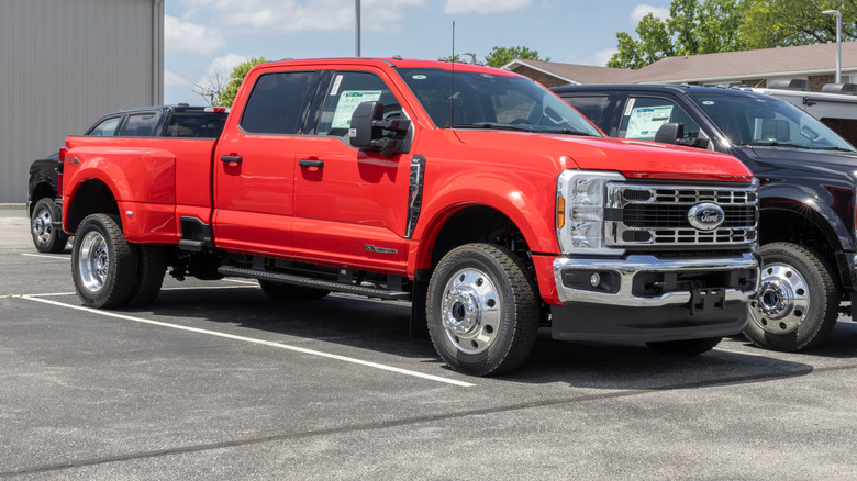 A red Ford Super Duty F-450 truck parked in a lot with a black one right next to it.