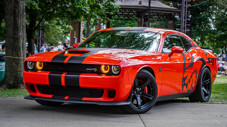 A red and black Dodge Challenger SRT Hellcat parked diagonally across a pavement.