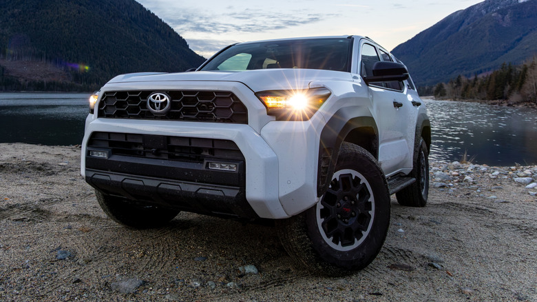 A Toyota 4Runner parked next to a tranquil lake around dusk time.
