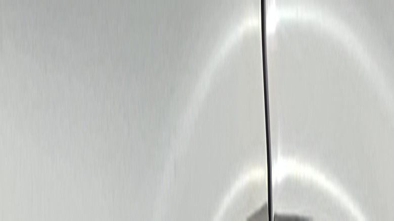 Silver RAM 2500 ProMaster badging on a whitish-gray vehicle, close up, on a sunny day.