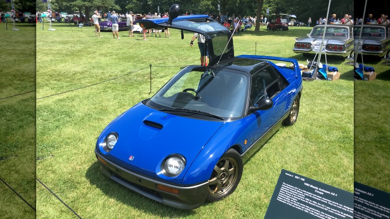 Blue Autozam AZ-1 parked on grass at a car show with one door open