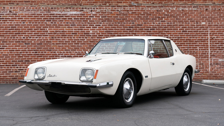 White Studebaker Avanti R2 parked in front of a brick wall
