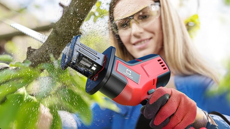 A woman using a Cerycose Reciprocating Saw on a tree branch.
