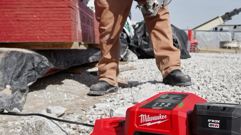 A Milwaukee Super Charger and battery on a rocky ground.