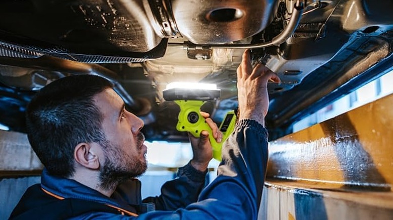 man using LED light under vehicle