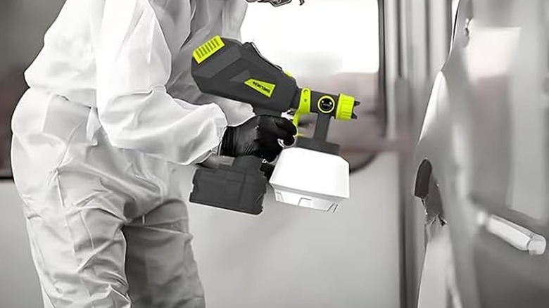 man using paint sprayer on car