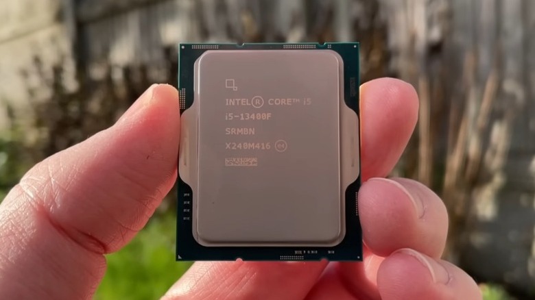 Fingers holding an Intel Core i5-13400F CPU outdoors