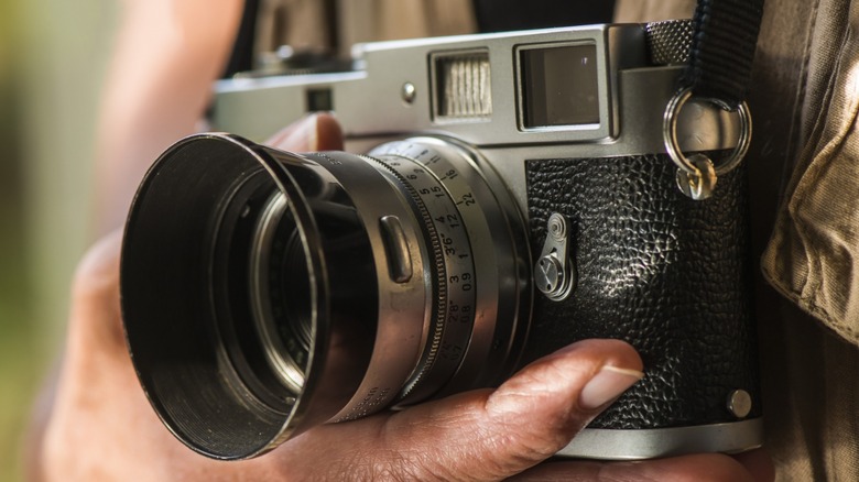 a film rangefinder camera worn on a strap by a photographer