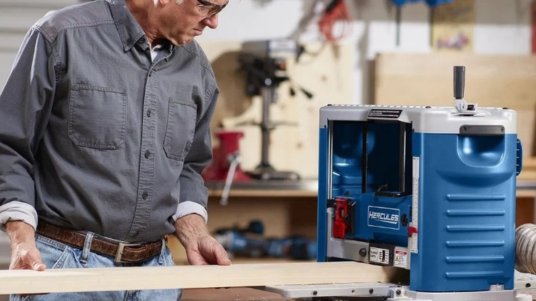 Carpenter feeding board into Hercules 15 Amp 12 ½-inch Portable Thickness Planer