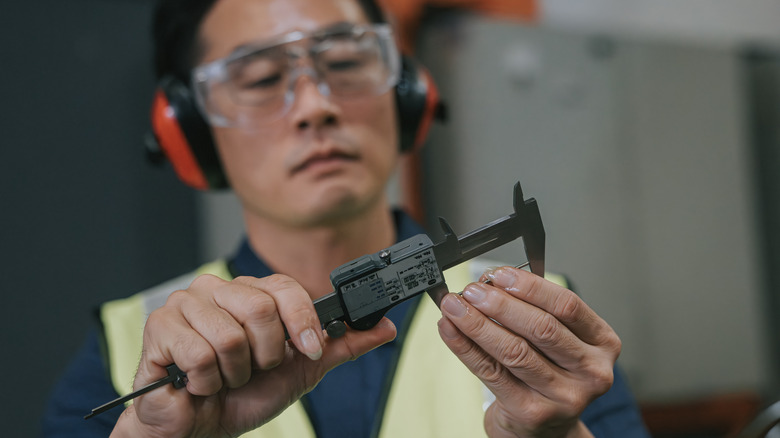 Worker using caliper on component