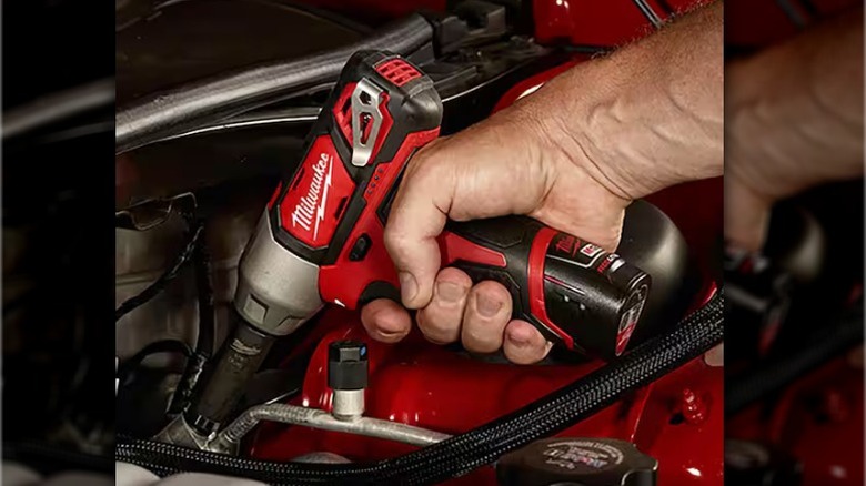 Person using Milwaukee M12 Cordless ⅜-inch Impact Wrench in car