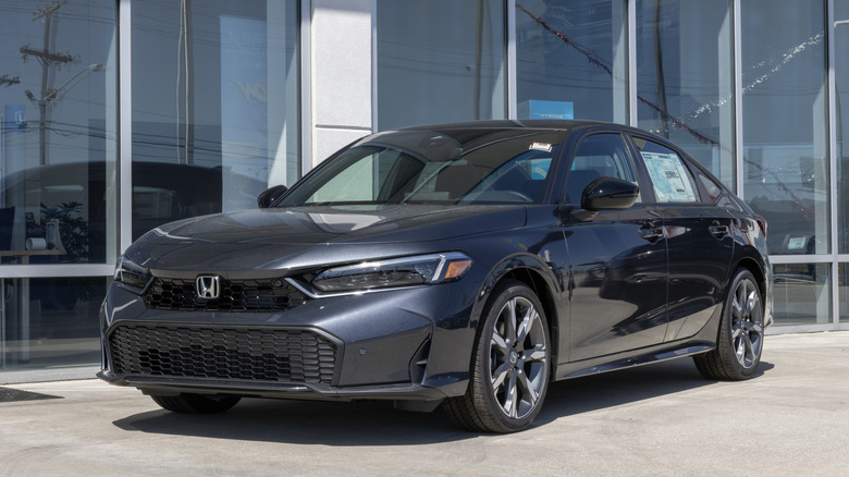 Front 3/4 view of gray Honda Civic Hybrid sedan parked at dealer.