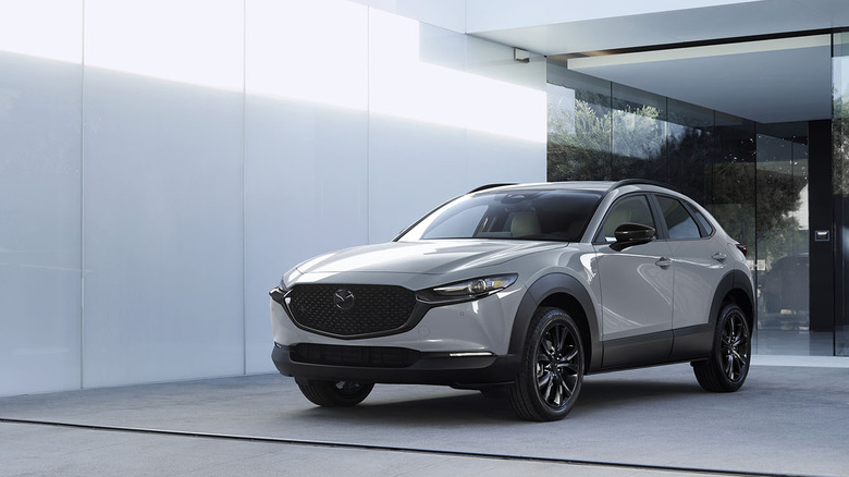 Front 3/4 view of gray Mazda CX-30 parked in front of building.