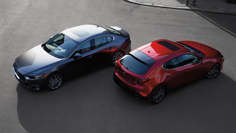 Overhead view of gray Mazda3 sedan and red Mazda3 hatchback parked on street.