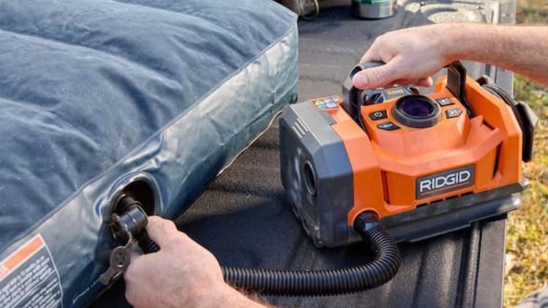 Person using Ridgid 18V Dual Function Cordless Inflator on air mattress