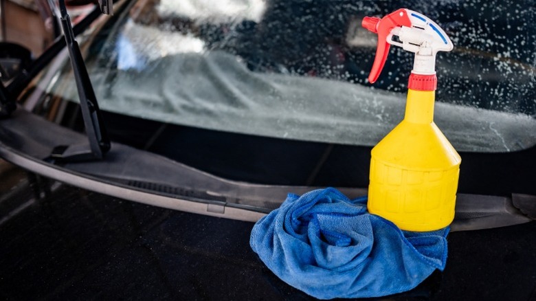 A spray bottle and microfiber cloth on a car