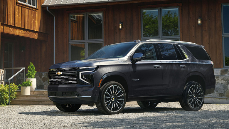 Front three-quarter view of black 2026 Chevy Tahoe parked in front of lodge.
