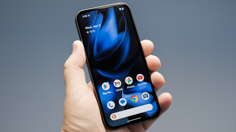 New Google Pixel 9a Android smartphone being held by a hand and showing the home screen.