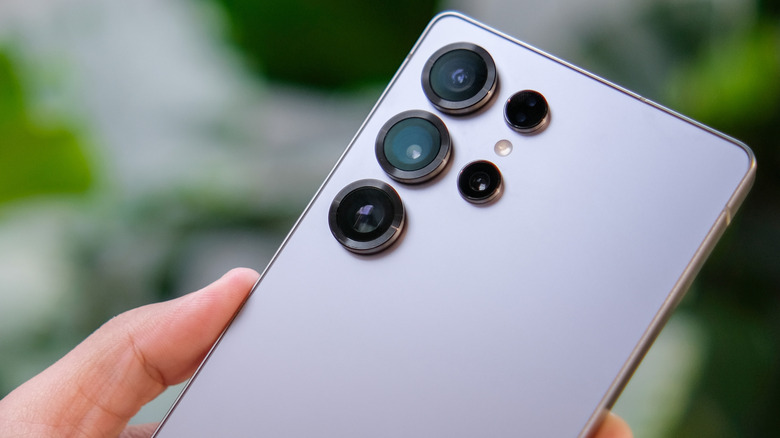 The Samsung Galaxy S25 Ultra being held by someone in front of a green blurred background.
