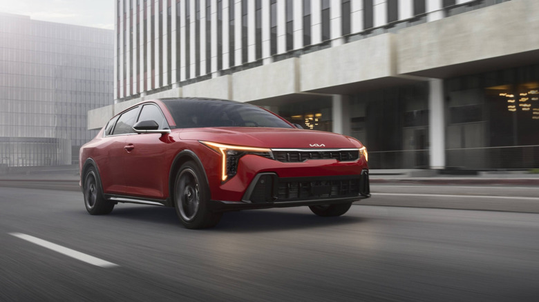 A red 2026 Kia K4 cruising along a city street