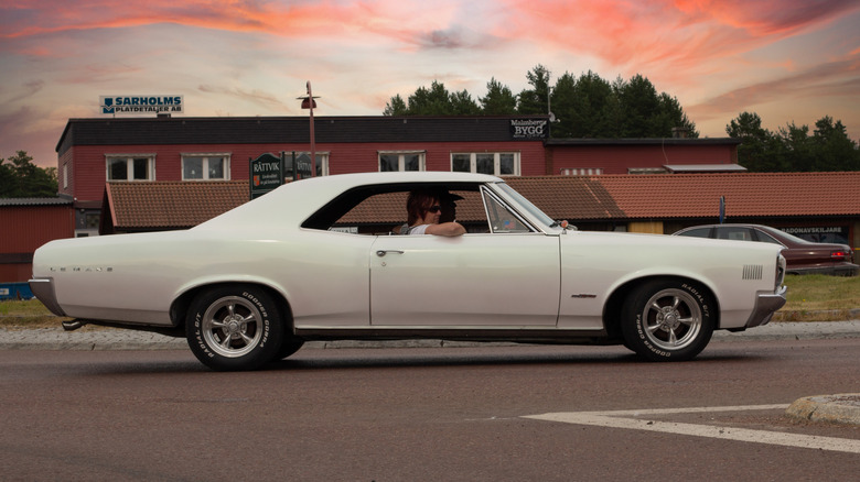 1966 Pontiac LeMans 2-door coupe driving on road at sunset, right-side view